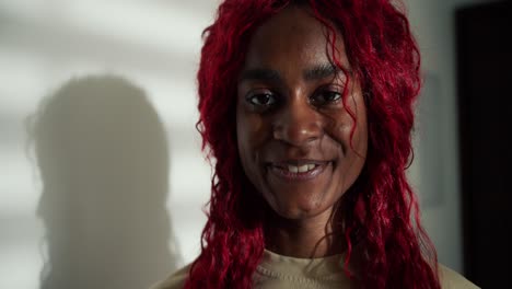 portrait of a happy carefree african american woman with red colored hair, smiling to the camera