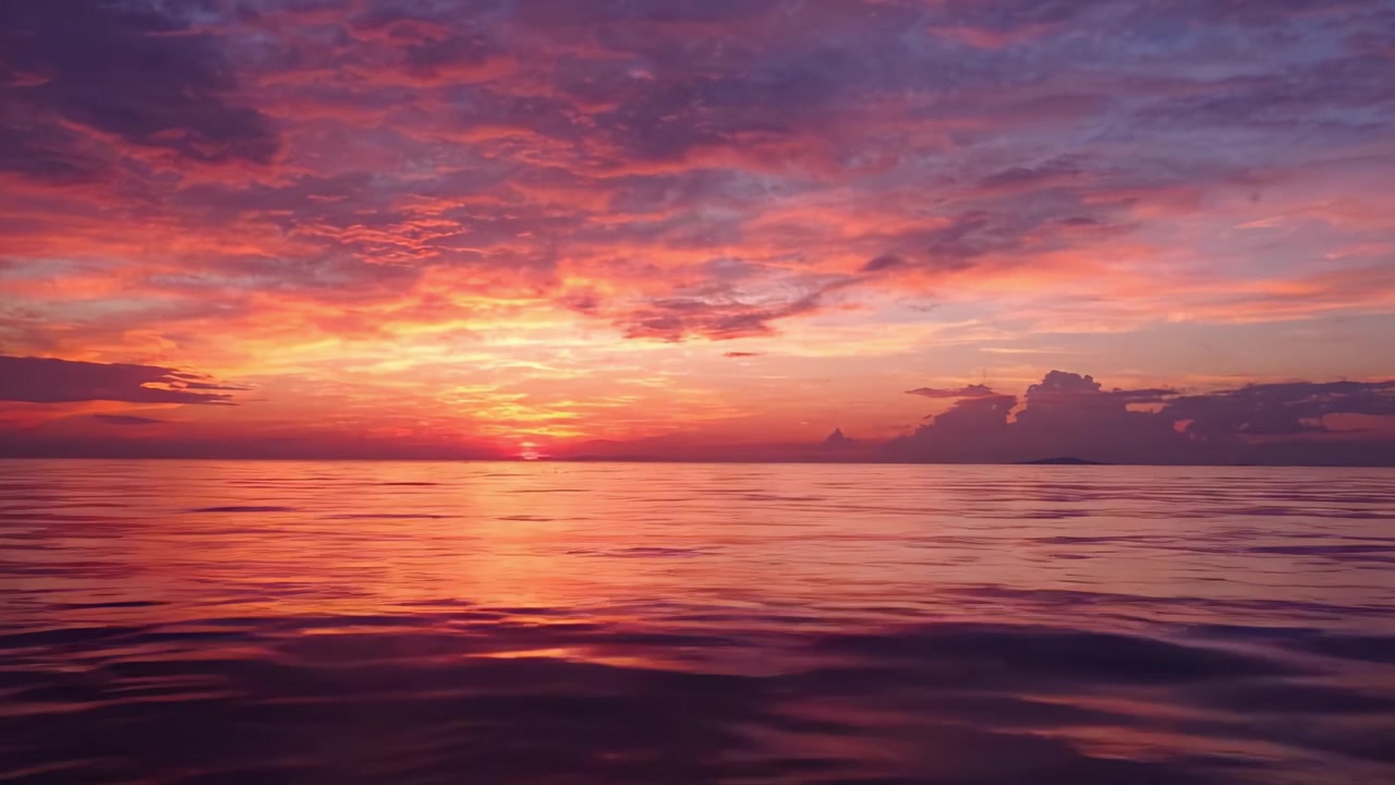 Matahari Terbenam yang Memukau di Atas Perairan Tenang, Menampilkan Awan Dramatis dan Warna Cerah di Cakrawala Saat Siang Beralih ke Malam, Menciptakan Suasana Tenang untuk Refleksi