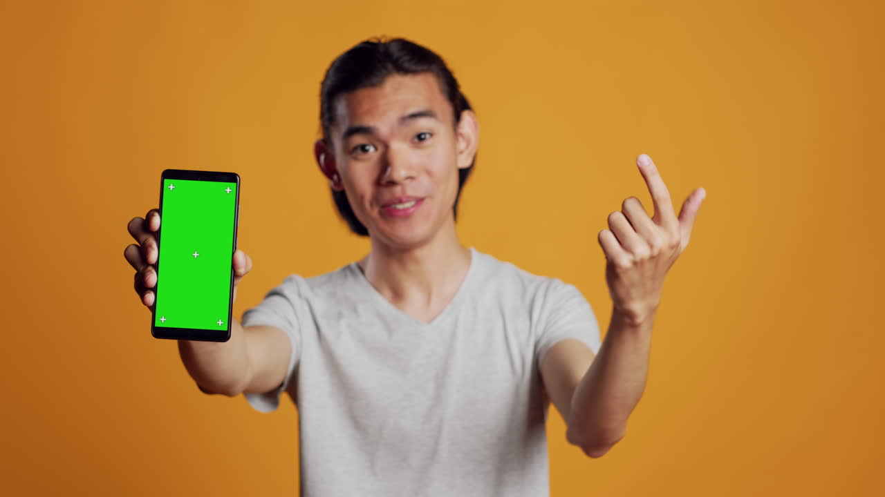 Positive man using greenscreen display on mobile phone