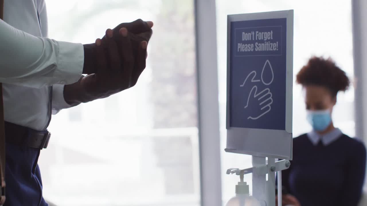 아프리카계 미국인 사업가가 사무실에 도착했을 때 손을 소독하는 중간 섹션