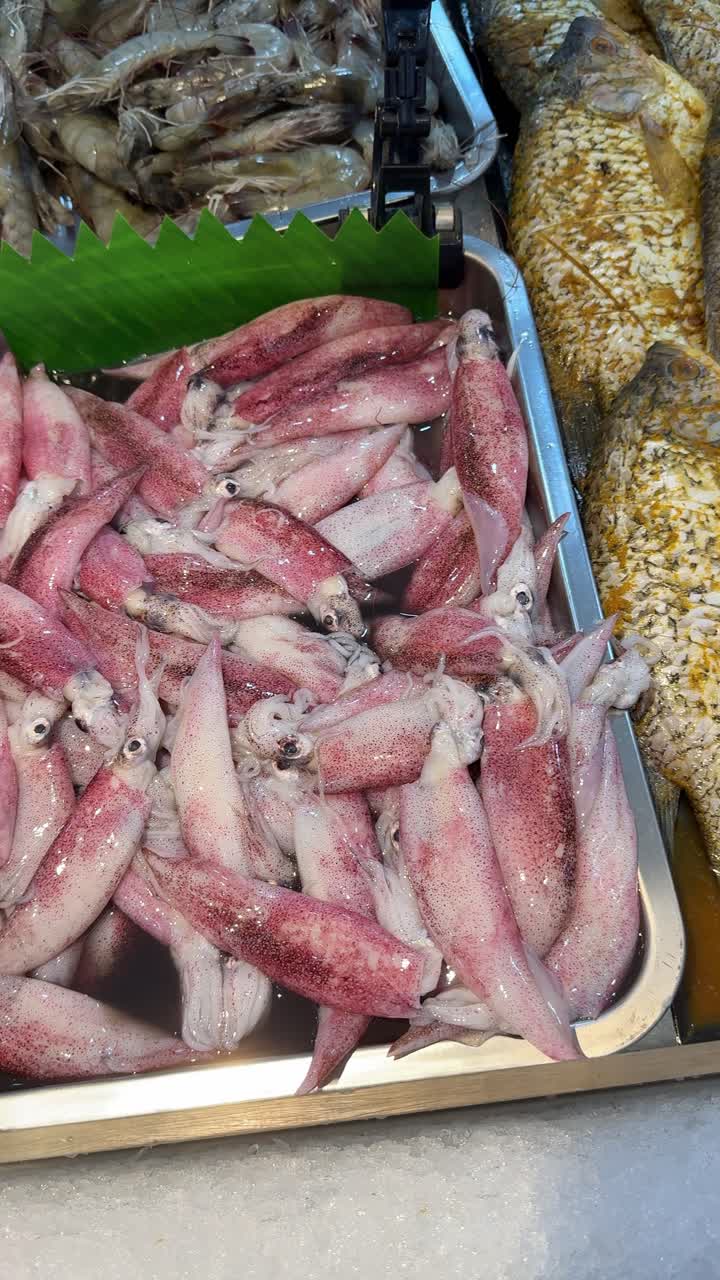 Pesce fresco e calamari esposti sul ghiaccio in un mercato del pesce