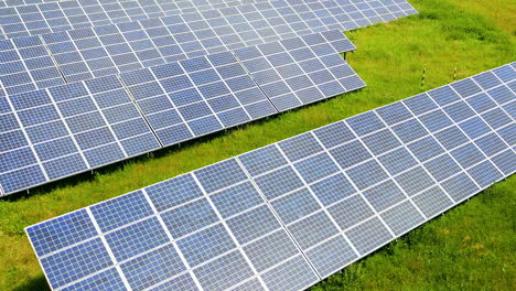 Aerial-track-shot-of-eco-friendly-solar-panels-farm-producing-clean-energy-during-hot-summer-day-with-sunlight-and-sunbeam-on-rural-pasture