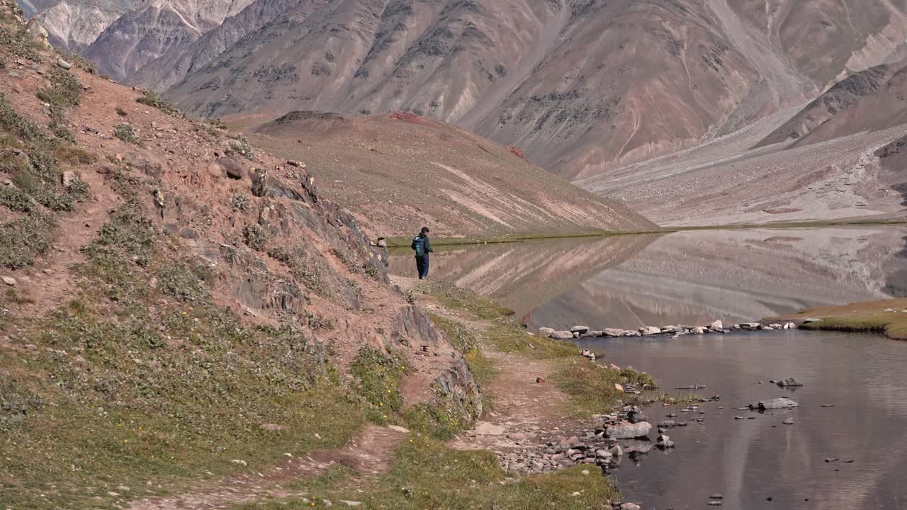 un hombre parado al borde de un hermoso lago himalaya