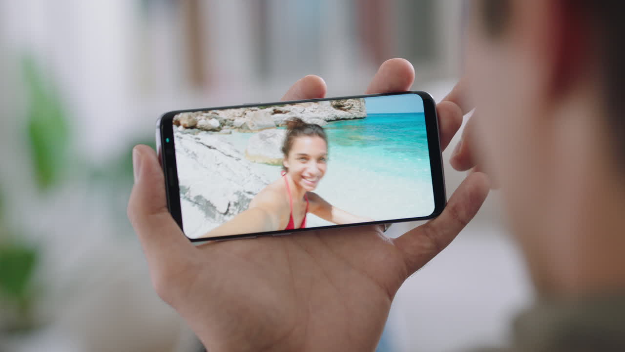 joven chateando por video usando un teléfono inteligente con su novia en una playa de vacaciones en italia compartiendo experiencia de viaje divirtiéndose en vacaciones chateando con un teléfono móvil 4k