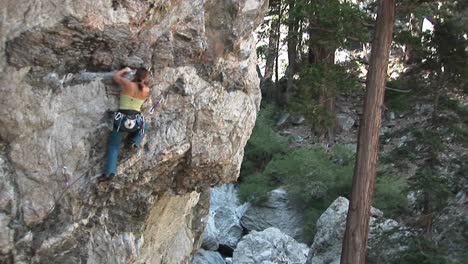 panup of a rock climber making her way up a perpendicular rock cliff face