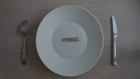 Revelar-Un-Plato-Blanco-Con-Azúcar-De-Palabra,-Concepto-De-Consumo-De-Azúcar