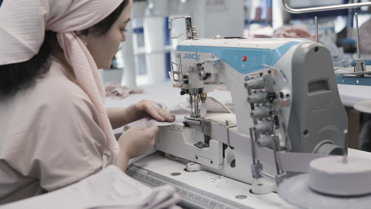 공장에서 바느질 기계에서 바느질하는 여자