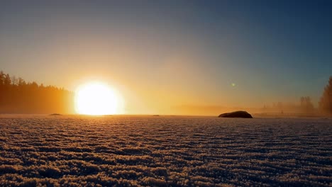 stunning timelapse showing golden sunset over foggy frozen lake with winter mist dancing above the ice, january in finland