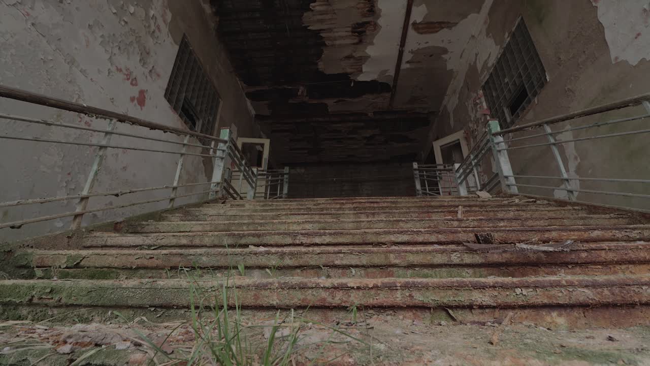 imágenes deslizantes de la parte inferior de una escalera principal en descomposición en una vieja escuela abandonada