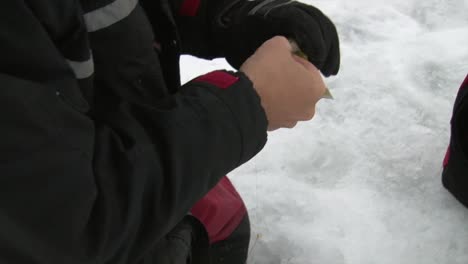 a man is taking hook out of fish during ice fishing