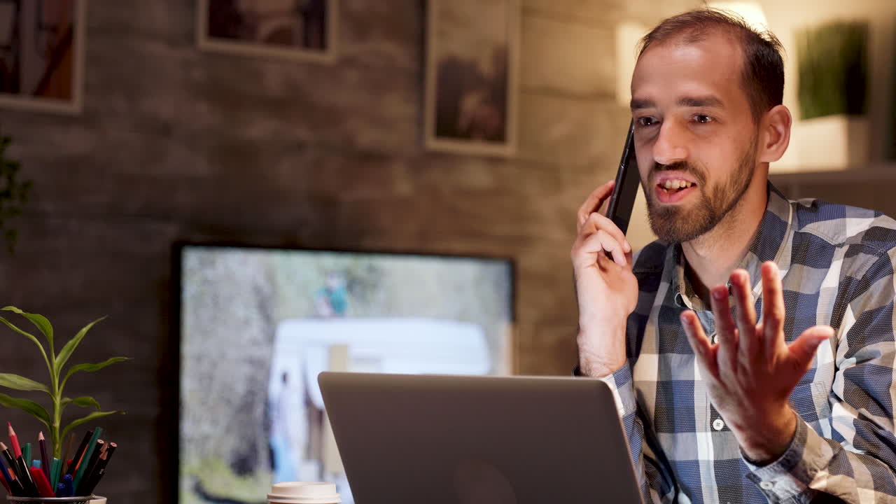 Man talking on the phone while working on his laptop