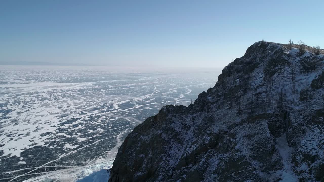 vista aérea del cabo khoboy, isla de olkhon. rocas altas en el lago congelado baikal con mucha gente y coches alrededor. destino turístico popular. paisaje de invierno. vista panorámica