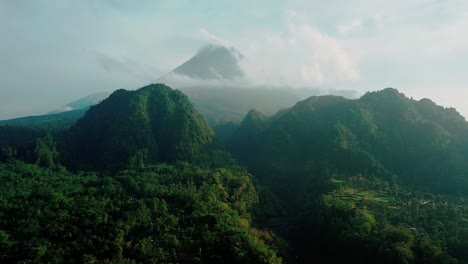 drone shot of merapi volcano with two hills and overgrown with dense forest