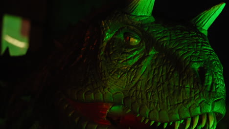 head of an illuminated predator dinosaur moving in a theme park for children