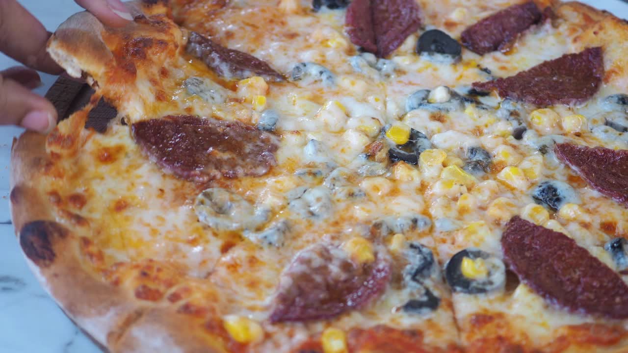 Una mano prende una fetta di deliziosa pizza con formaggio fuso