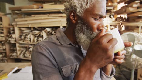 African-american-male-carpenter-drinking-coffee-in-a-carpentry-shop