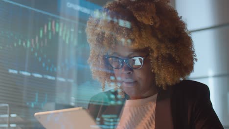 african american woman working on tablet in office at night