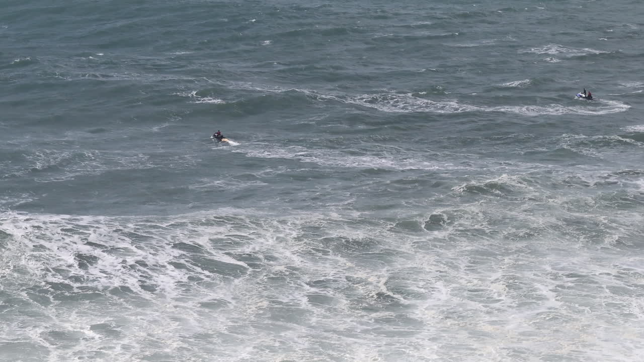 Jet ski teams entering massive Nazaré waves, aerial drone capture. Portugal, Europe
