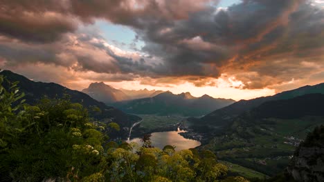 Orange-sun-rays-fall-on-Alpine-Lake-Walensee-at-golden-hour-reflecting-vibrant-sky