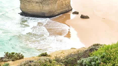 dynamic coastal scene with waves hitting the shore at twelve apostles, captured in bright daylight with vibrant colors