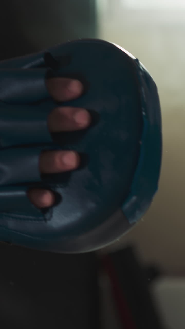 niño patea la almohadilla por la pierna con el entrenador en el gimnasio de primer plano. instructor de combate lleva a cabo el entrenamiento con la niña en la escuela de deportes en cámara lenta. pasatiempo de los niños