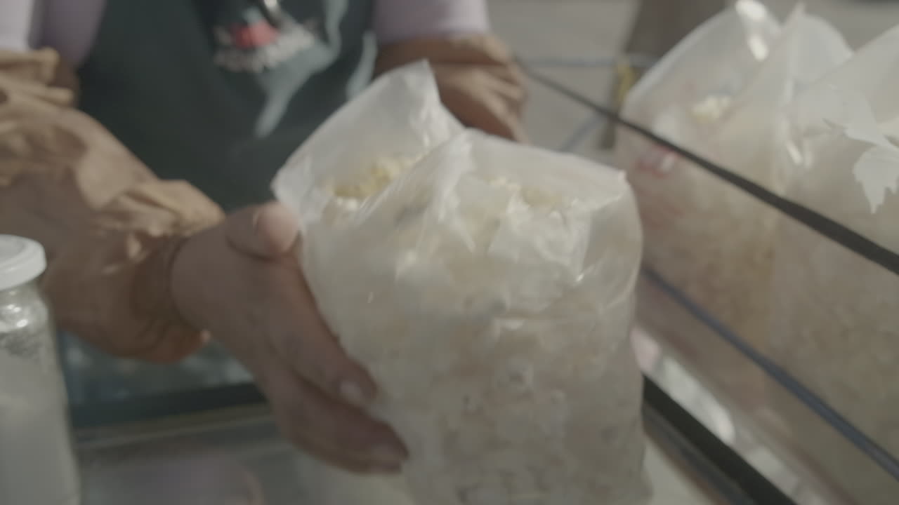 Slowmotion shot of lady preparing and seasoning a bag of popcorn LOG