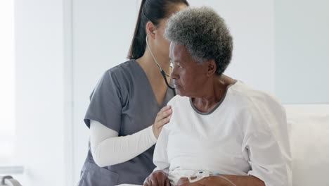 Diverse-female-doctor-testing-senior-female-patient-using-stethoscope-in-hospital-room,-slow-motion