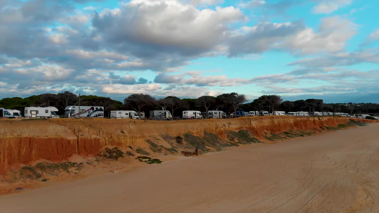 Beach in a cloudy day with a cliff and pines on top