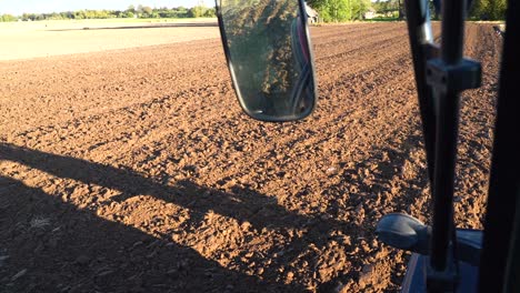 plowing arable land with heavy tractor, pov driving cabin