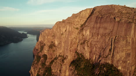 breathtaking aerial view of an impressive cliff in norway, sunrise atmosphere in the lysefjorden, preikestolen, pulpit rock, drone going upwards