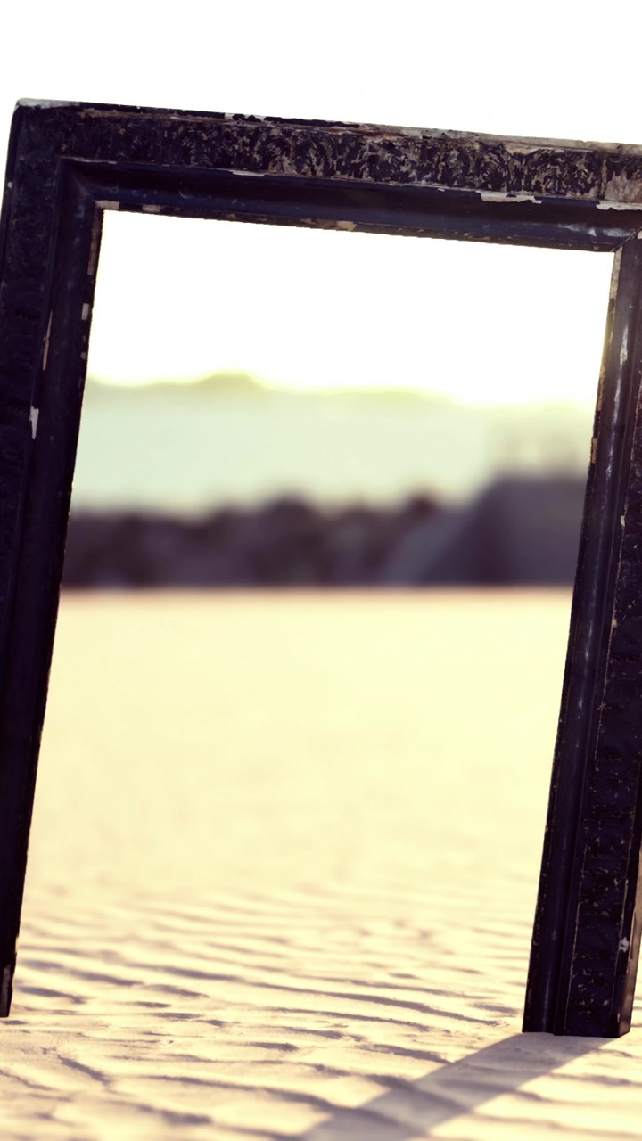 Black frame standing on sand with background of hills and sunlight