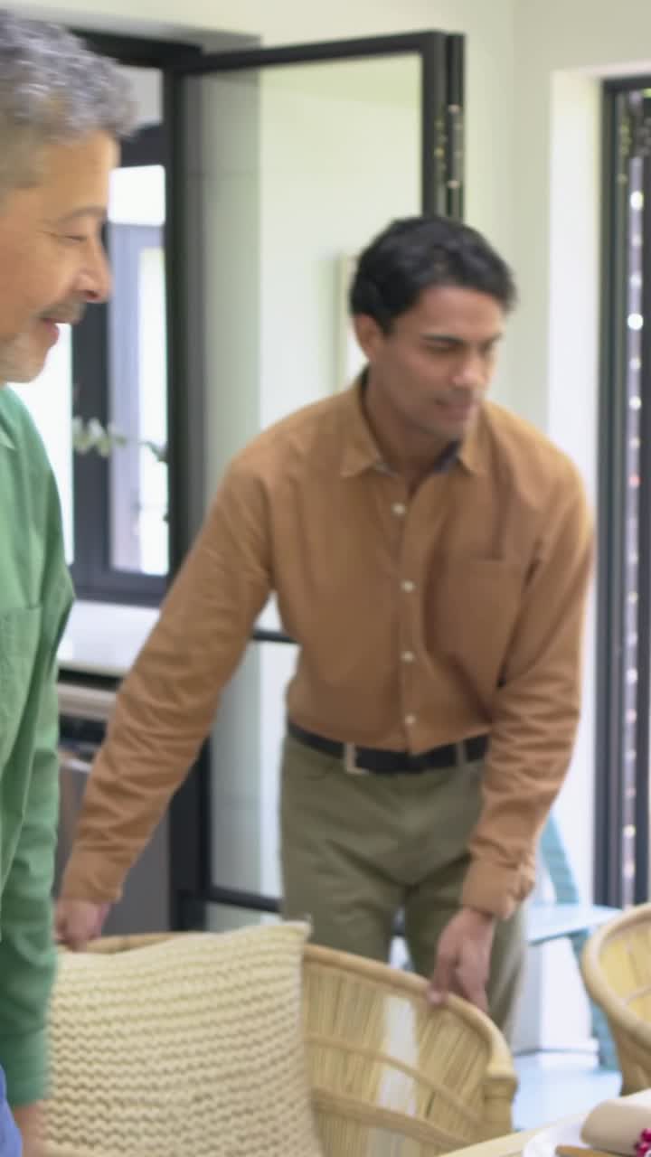 Video verticale: Un uomo in camicia color cuoio porta una ciotola in cucina, sistema il tacchino mentre sono seduti a condividere un pasto