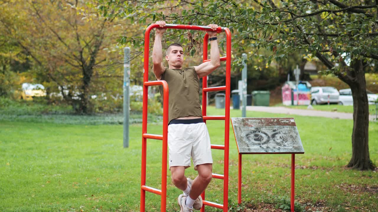 hombre atlético musculoso entrenando con pull-ups en una pieza de equipo deportivo en el parque