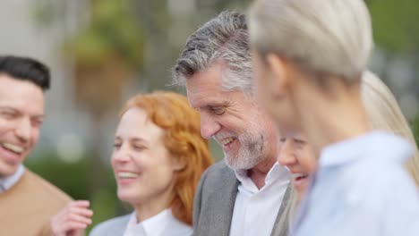 group of happy business colleagues laughing and interacting outdoors
