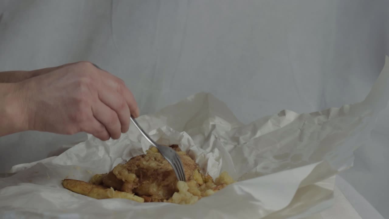 Hand eating traditional British fish and chips take away meal medium shot
