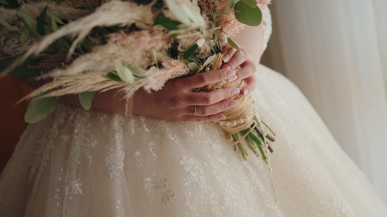Bride holding a rustic bouquet with pampas grass and greenery in soft natural light