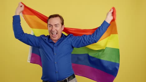 a man enthusiastically celebrates pride with a rainbow flag.