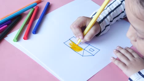 girl drawing a house with markers