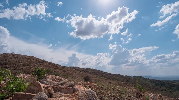 Hermoso timelapse en movimiento de nubes en el cielo azul sobre una colina cubierta de piedras.