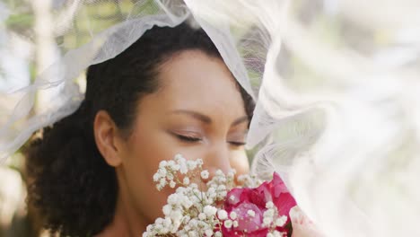 Happy-african-american-woman-with-flowers-wearing-wedding-dress