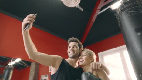abrazando a una pareja de fitness posando para un teléfono móvil para una selfie en el club de gimnasia.