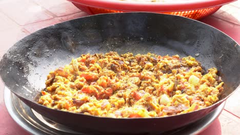 spicy scrambled eggs with tomatoes and onions in a wok