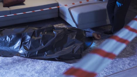 un policía mirando la bolsa del cadáver en la escena del crimen.