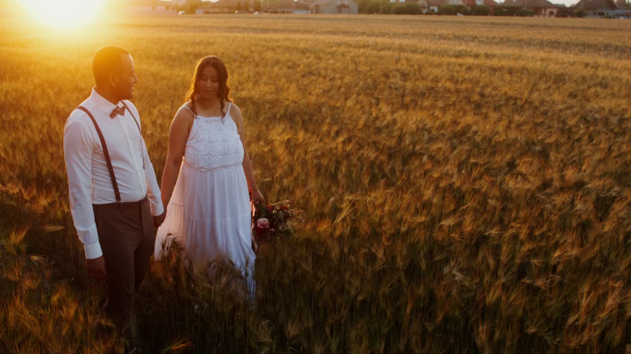 pareja caminando en un campo de trigo al atardecer