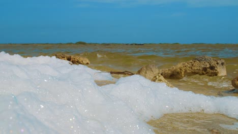 saltwater foam washed ashore with sea waves on the background in kralendijk, bonaire