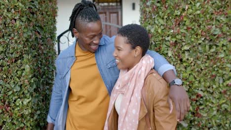 Glückliches-Afroamerikanisches-Paar,-Das-Sich-Umarmt-Und-Vor-Dem-Haus-Steht,-Zeitlupe