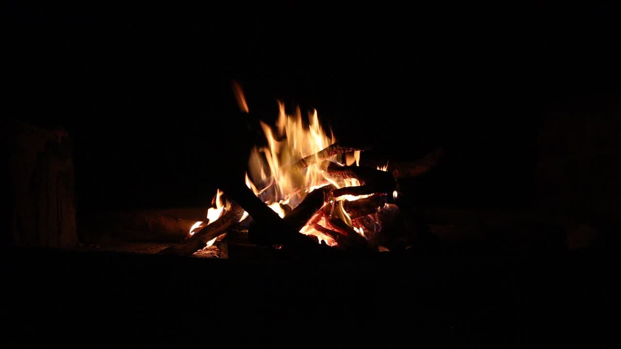 una gran hoguera de campamento ardiendo brillantemente en una noche oscura