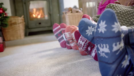 feet of african american family in warm socks by fireplace in living room, copy space, slow motion