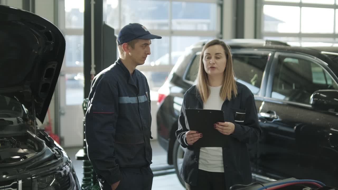 gerente femenina discutiendo la reparación de vehículos con el mecánico en el taller de reparación de automóviles