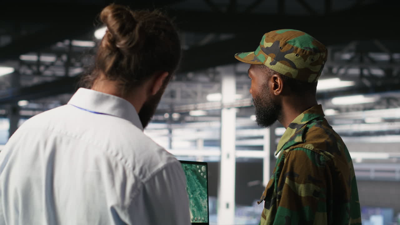 Military experts in data center reviewing drone surveillance feed on laptop